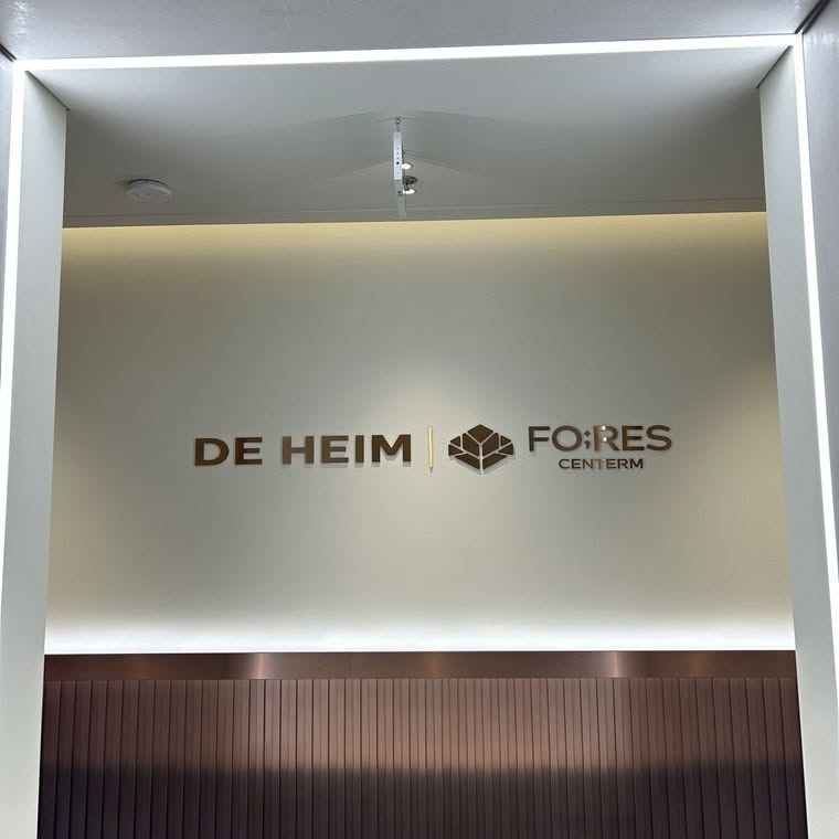 Logo DE HEIM đặt cạnh logo dự án Fores Centerm trên tường tại khu vực trưng bày dự án